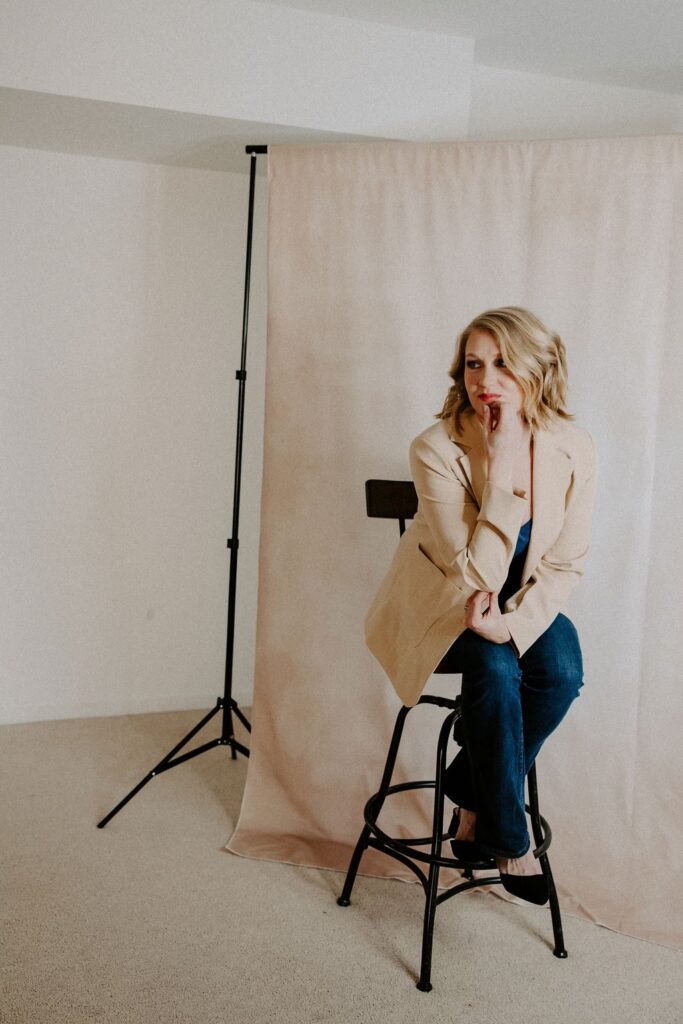 blonde girl on chair with beige blazer, head on her hand