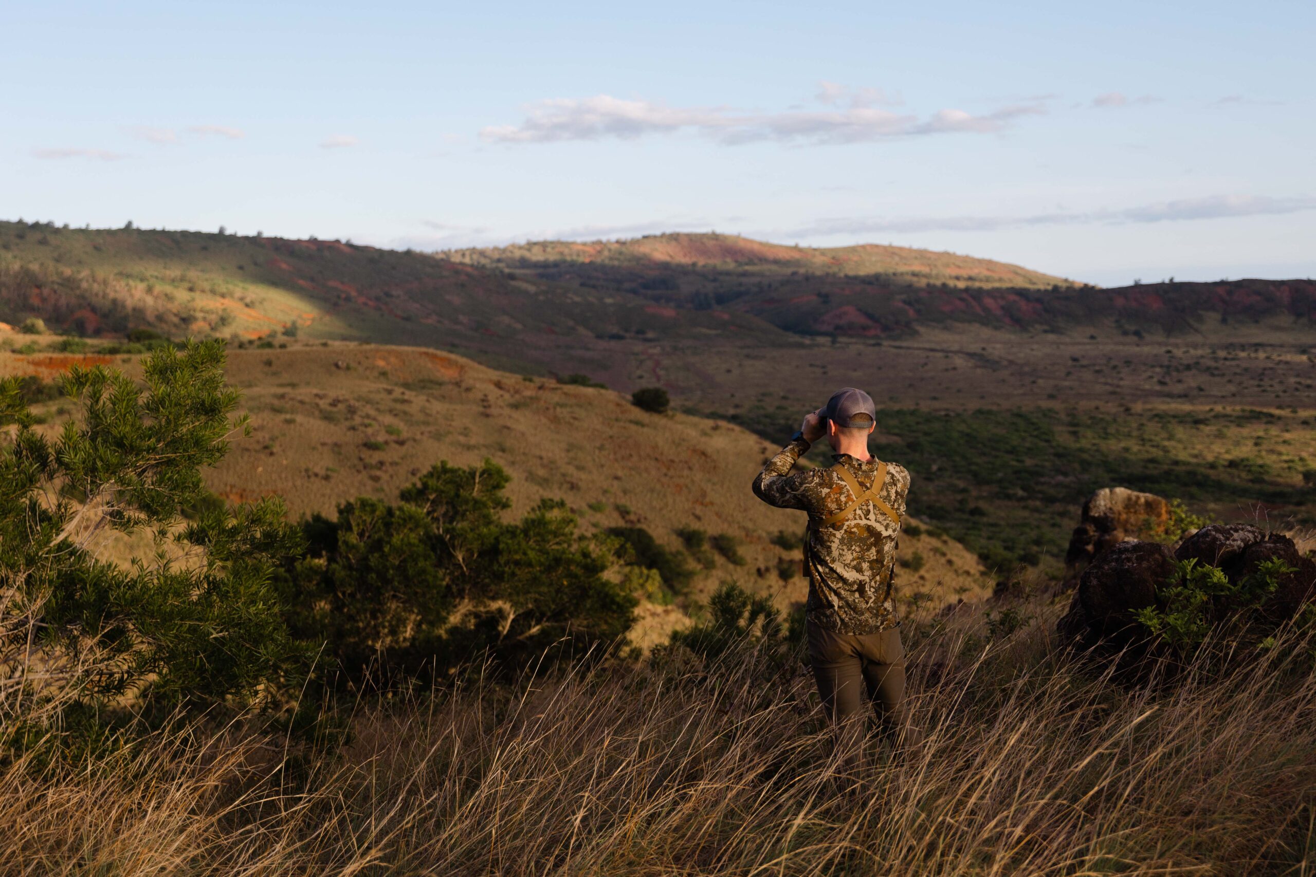 man in camo looking through binoculars